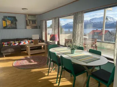 a living room with a table and chairs and a large window at EIDE Gjestehus in Eide