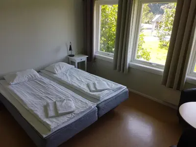 a bed in a bedroom with two windows at Folgefonn Gjestetun in Jondal