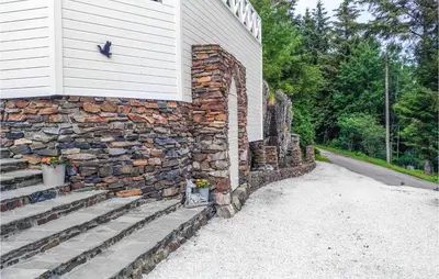 a stone retaining wall with stairs next to a house at Amazing Apartment In Fjell in Lokøy