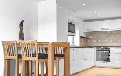 a kitchen with white cabinets and a table and chairs at Amazing Apartment In Fjell in Lokøy