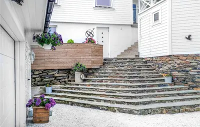 a set of stairs in front of a house with flowers at Amazing Apartment In Fjell in Lokøy