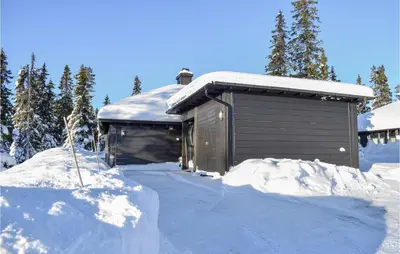 a building covered in snow next to a pile of snow at Stunning Home In Sjusjøen With Sauna in Sjusjøen