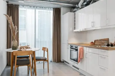 a kitchen with white cabinets and a table and chairs at Aalesund City Apartment in Ålesund
