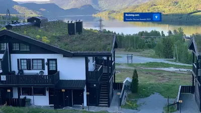 a house with a green roof with a lake in the background at Norefri apartment with sauna at Nedre Norefjell Ski In- Ski Out in Noresund