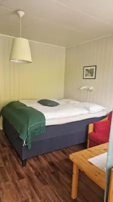 a bedroom with a large bed and a red chair at Kvamsdal Pensjonat 3 in Eidfjord