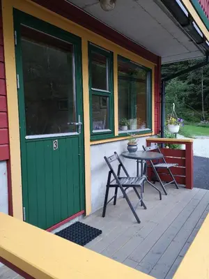 a porch of a house with a green door and a table at Kvamsdal Pensjonat 3 in Eidfjord