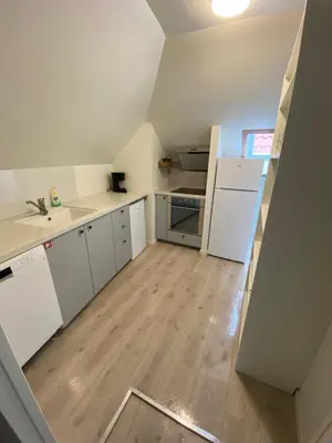 a kitchen with white cabinets and a wooden floor at Nice central appartment in Bergen