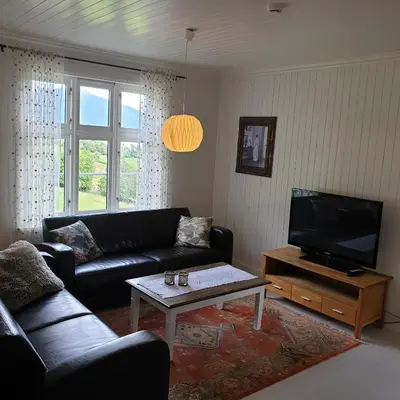 a living room with a couch and a flat screen tv at Irenegarden - Fjord view holiday home in Lauvstad