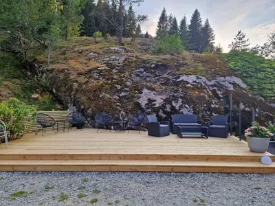 a wooden deck with chairs and chairs on top of a hill at Kvamsdal Pensjonat 4 in Eidfjord
