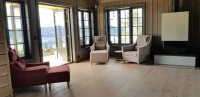 a living room with chairs and a tv and windows at Mjøshytte in Stange