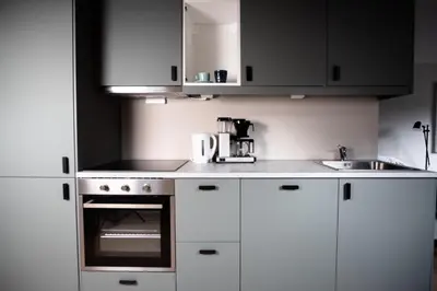 a kitchen with white cabinets and a stove top oven at Trolltunga Odda Apartments in Odda