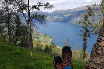 a person with their feet up on a hill overlooking a lake at Nordfjordcabins RED in Utvik
