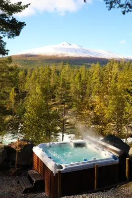 a jacuzzi tub with a mountain in the background at Pollfoss Boutique Hotel & Spa in Skjåk