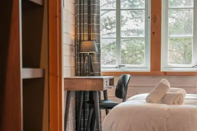 a bedroom with a bed and a desk and windows at Pollfoss Boutique Hotel & Spa in Skjåk