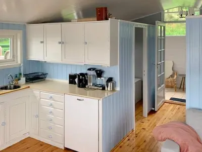 a kitchen with white cabinets and blue walls at 6 person holiday home in LINDÅS in Lindås