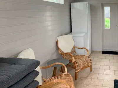 a bedroom with a bed and two wicker chairs at 6 person holiday home in LINDÅS in Lindås