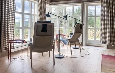 a room with three chairs and a table and windows at Moltebæret in Skåbu