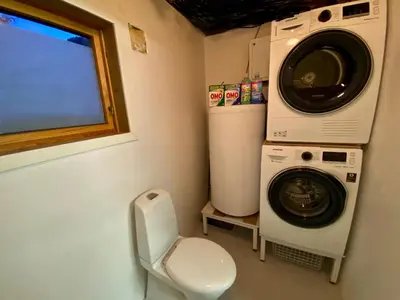 a small bathroom with a washing machine and a toilet at Askevika in Vikum