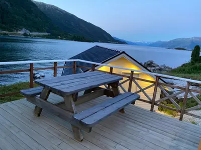 a picnic table sitting on a deck next to a lake at Askevika in Vikum