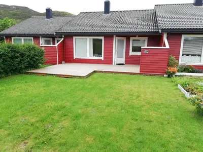 a red house with a lawn in front of it at Leinastova in Sandshamn