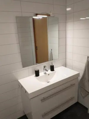 a bathroom with a white sink and a mirror at Leinastova in Sandshamn