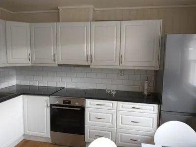 a kitchen with white cabinets and a black dishwasher at Leinastova in Sandshamn