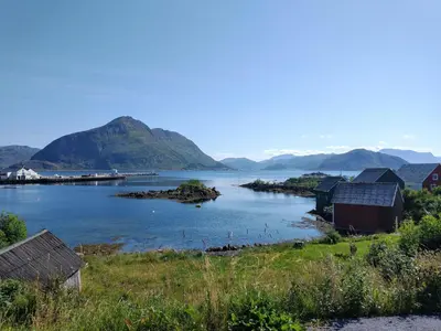 a view of a body of water with houses and mountains at Leinastova in Sandshamn