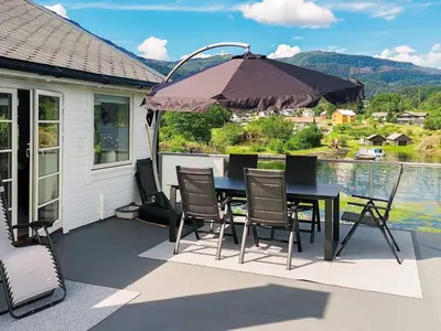 a patio with a table and chairs and an umbrella at Seaside Serenity in Hardangerfjord-By Traum in Tyrvikbygd