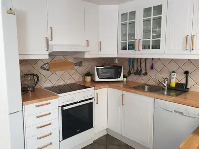a kitchen with white cabinets and a sink and a microwave at Bergen Apartment with Fjord View in Isdalsstø