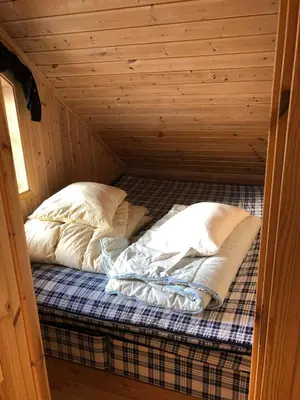 a bed in a wooden cabin with two pillows at Ramsbu utsikt terasse selvhushold in Hovden