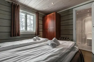 two beds in a room with a bathroom with a tub at Storelia in Hemsedal