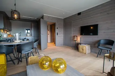 a living room with a table and chairs and a kitchen at Ridderleiligheter in Beitostøl