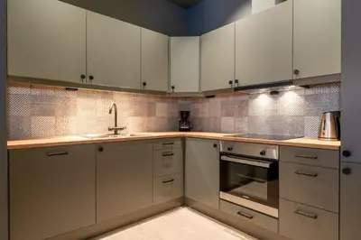 a kitchen with white cabinets and stainless steel appliances at Ridderleiligheter in Beitostøl