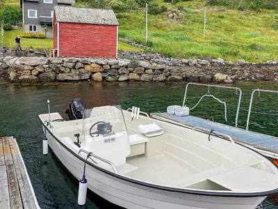a white boat docked at a dock with a red building at 8 person holiday home in Barmen in Barmen