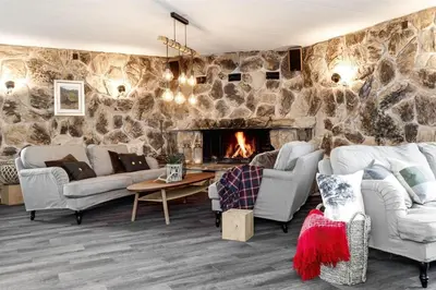 a living room with couches and a stone wall at Fossheim Lodge - arealeffektiv minileilighet in Torset