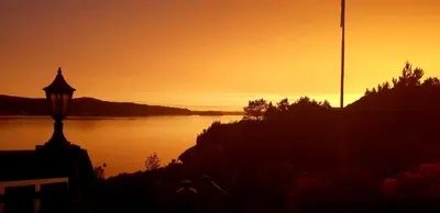 a sunset over a body of water with a street light at Ferienhaus „Draumen“ in Norwegen in Bømlo