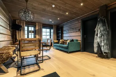 a living room with wooden walls and a green couch at Skigaarden in Hemsedal