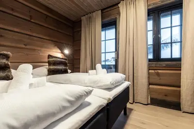 two beds in a room with wooden walls and windows at Skigaarden in Hemsedal
