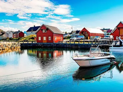 a boat in the water in front of a red house at 7 person holiday home in Bud in Bud
