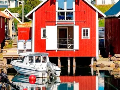 a boat is docked in front of a red house at 7 person holiday home in Bud in Bud