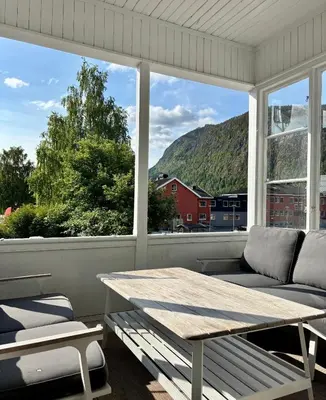 a screened in porch with a table and a couch at Apotekbygget in Nesbyen
