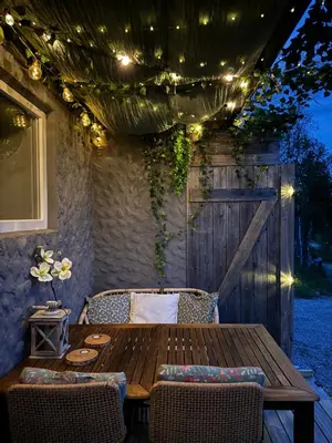 a wooden table and chairs on a patio with lights at Bjørkli Lodge in Geilo