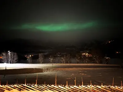 a green light in the sky over a snow covered field at Bjørkli Lodge in Geilo