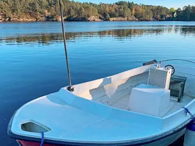 a blue boat sitting on the water on a lake at 6 person holiday home in HOSTELAND in Hosteland
