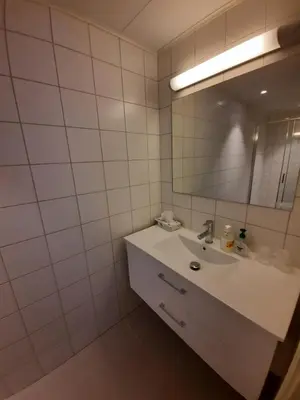 a white bathroom with a sink and a mirror at Sunndalsøra Hotell in Sunndalsøra