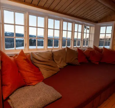 a large couch with pillows in a room with windows at Nordpå Fjellhotell AS in Haltdalen