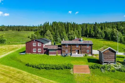 a large house on a green field with trees at Nordpå Fjellhotell AS in Haltdalen