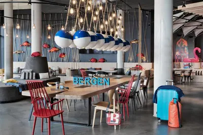 a restaurant with a wooden table and chairs at Moxy Bergen in Bergen