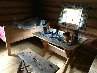 a room with a table and a bed and a table and bench at Drengstua på Dahl Østre in Stange
