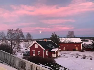 a red house in the snow with the moon in the sky at Drengstua på Dahl Østre in Stange